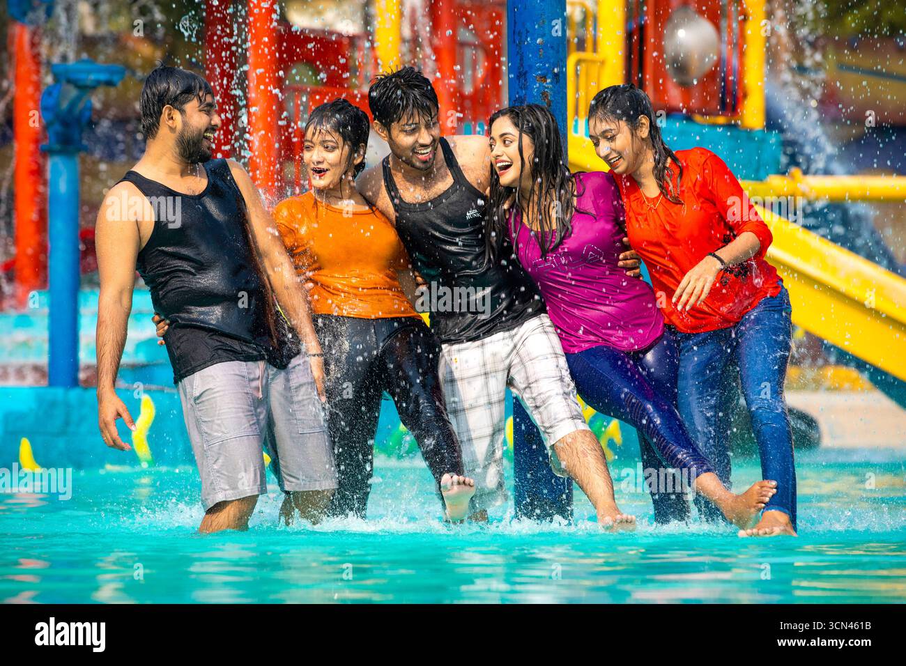 A Diverse Group of Friends Laughing and Embracing in a Water Park Pool During a Fun Summer Day Stock Photo