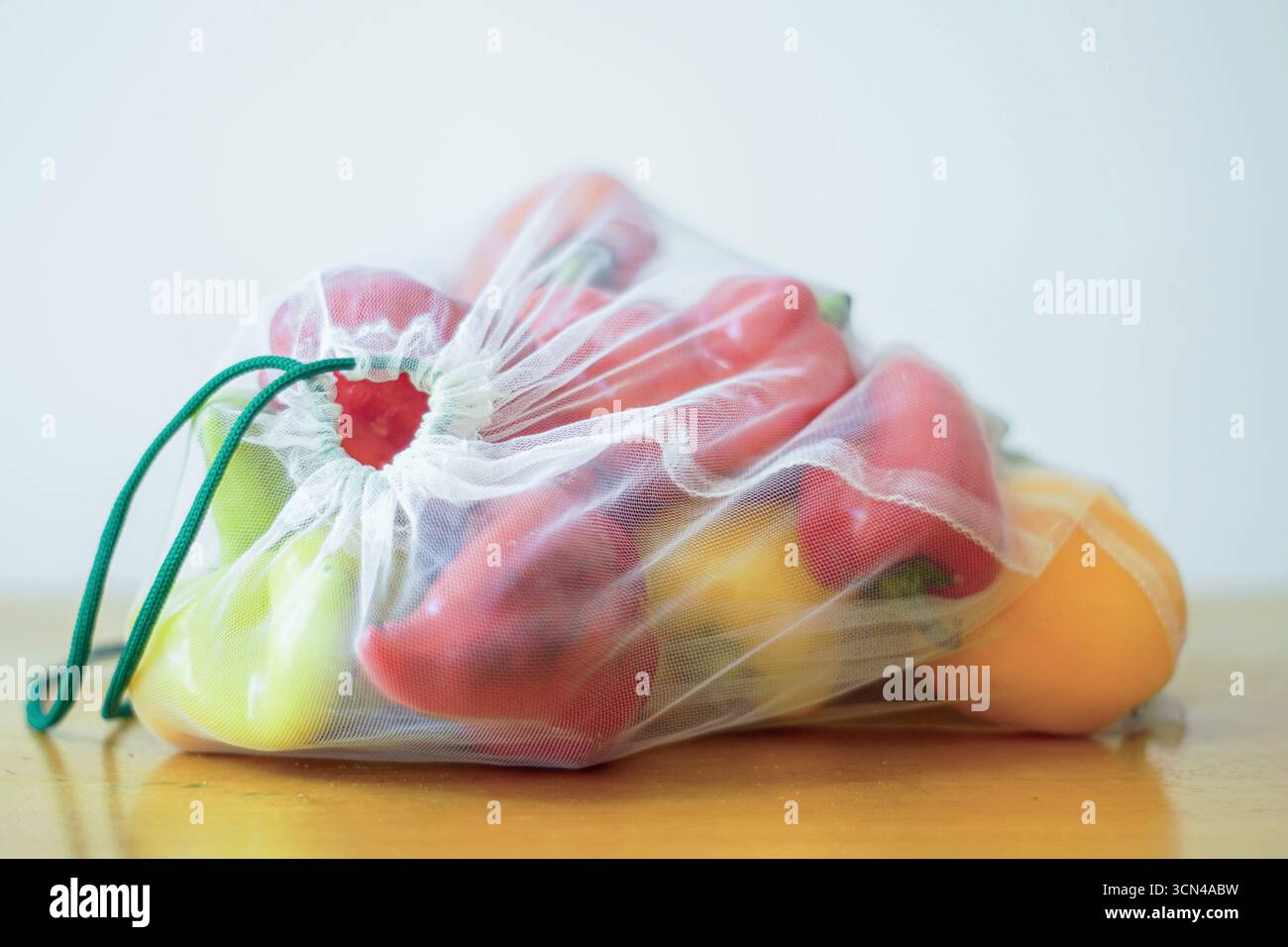 Colorful bell peppers in a reusable mesh bag. Vegetables in eco-friendly packaging with care for the environment. Green living and waste reduction Stock Photo