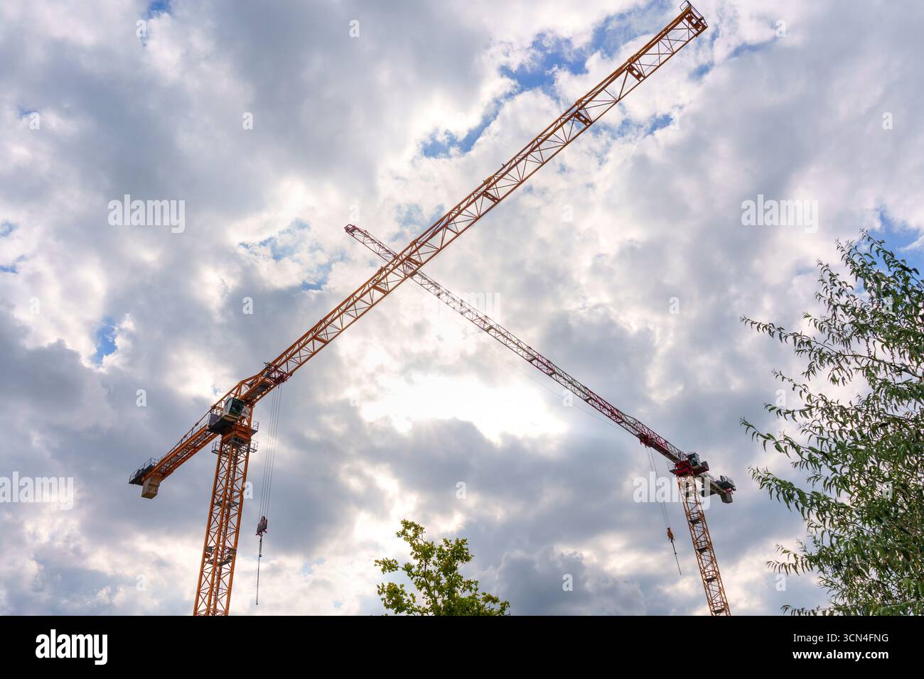 Berlin, Germany - August 20, 2025: Construction cranes towering against a backdrop of dramatic clouds, capturing urban development in Berlin, Germany. Stock Photo