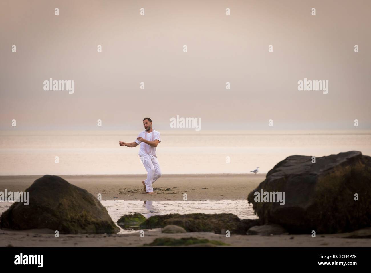 Man wearing white dancing in the beach on Cape Cod during the pi Stock Photo