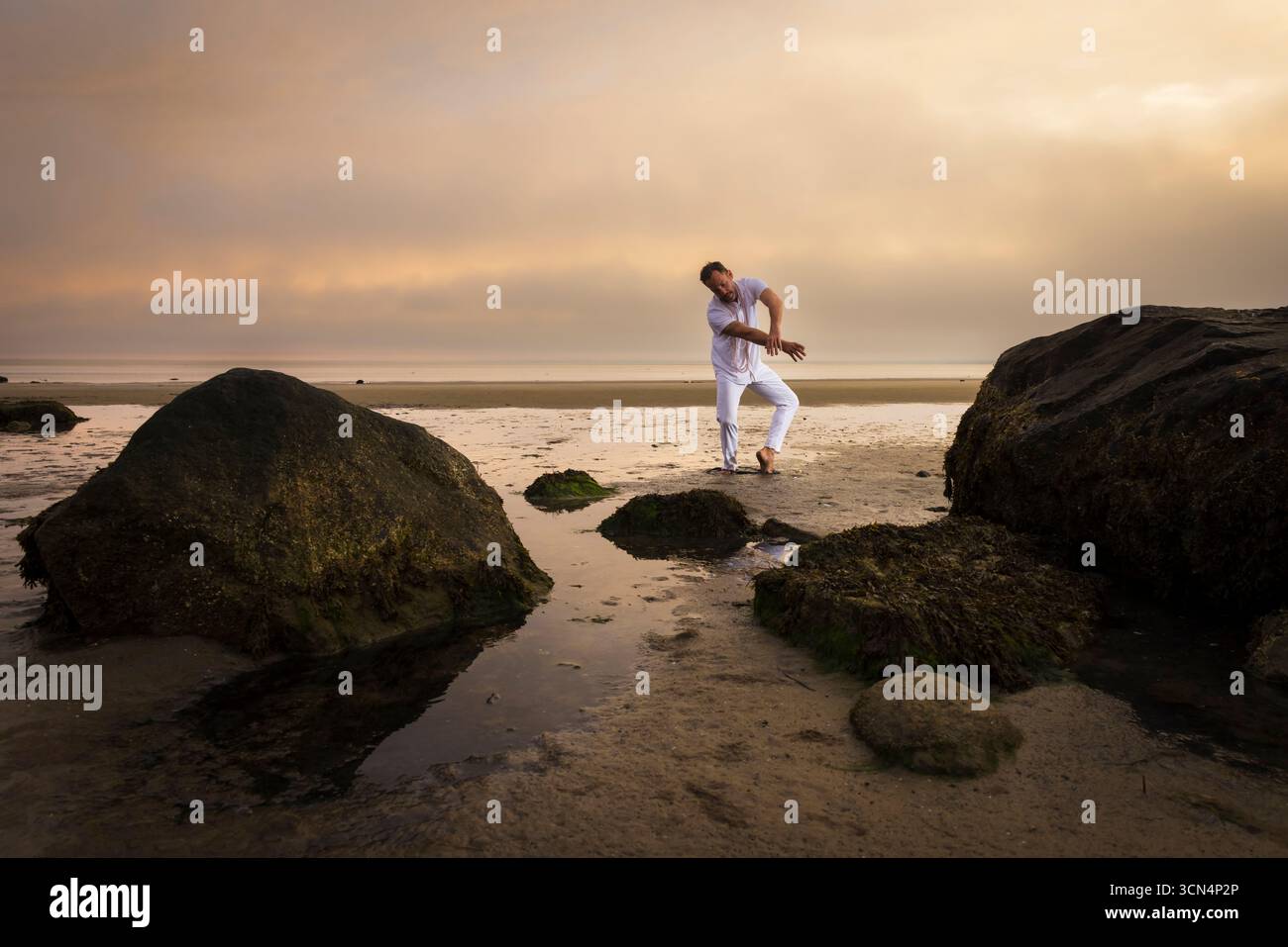Man wearing white dancing in the beach on Cape Cod during the pi Stock Photo