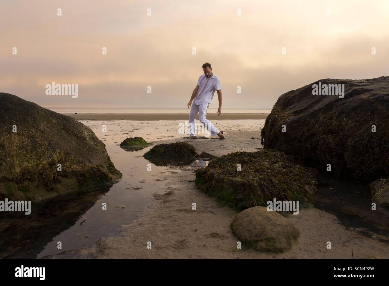 Man wearing white dancing in the beach on Cape Cod during the pi Stock Photo