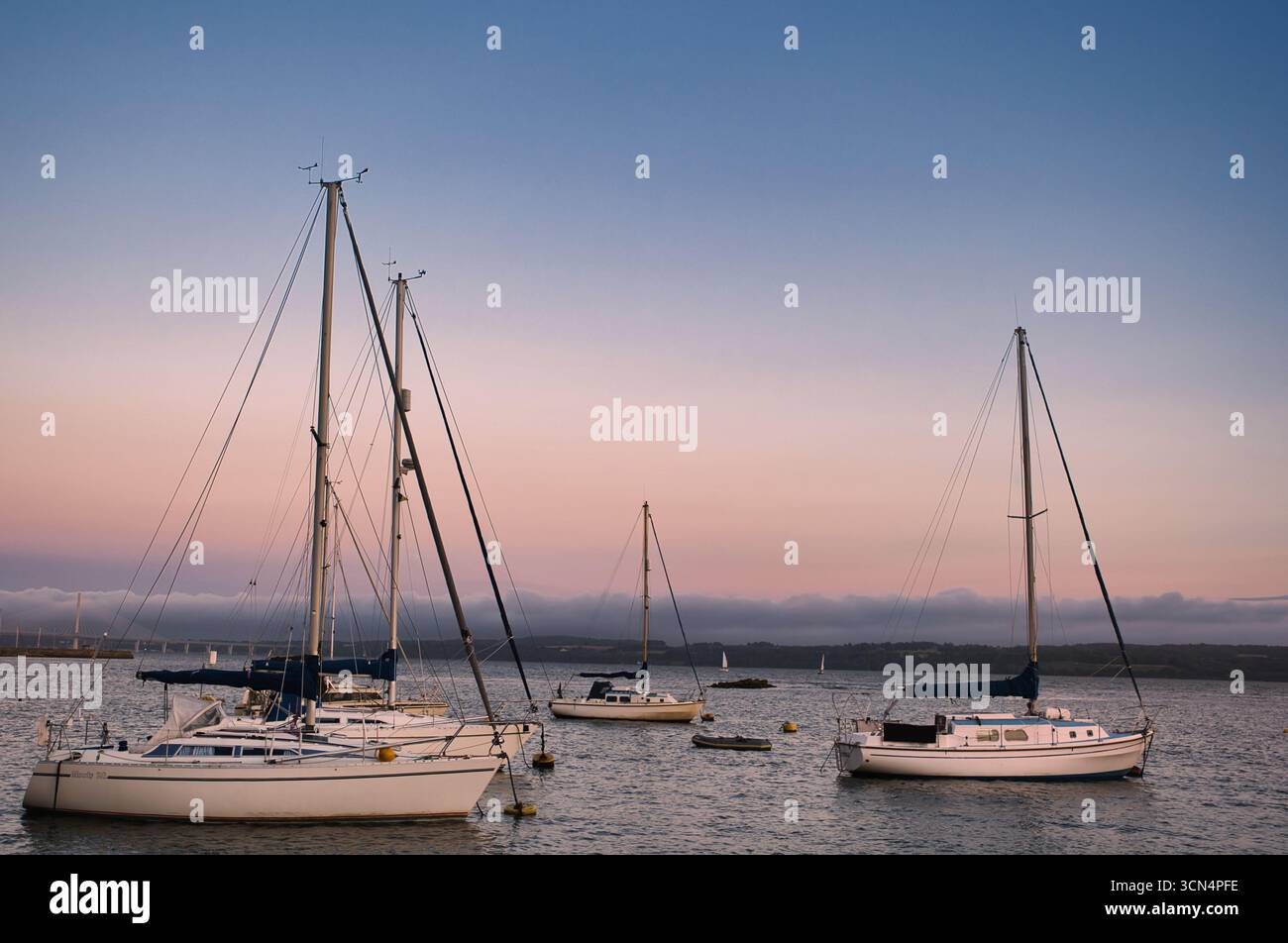 Sailboats in harbor at sunset with calm sea Stock Photo - Alamy