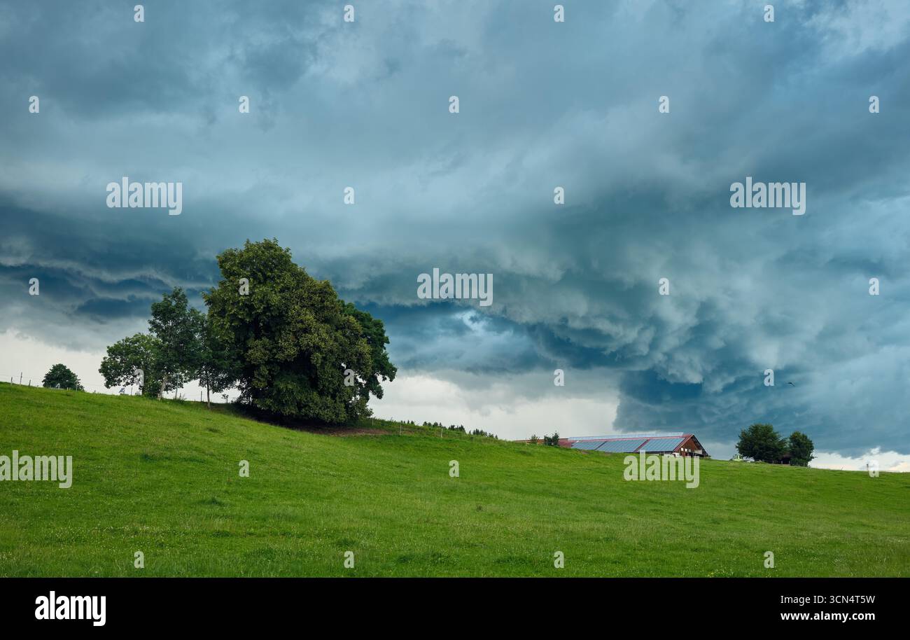 Dark storm clouds gathering over green hills Stock Photo