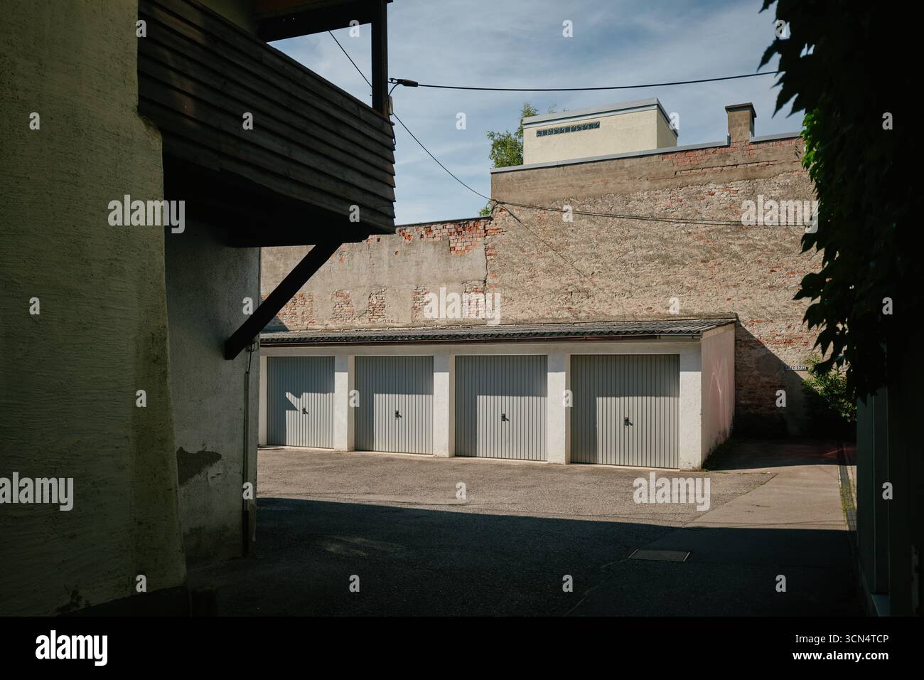 Four gray garage doors under a brick wall Stock Photo