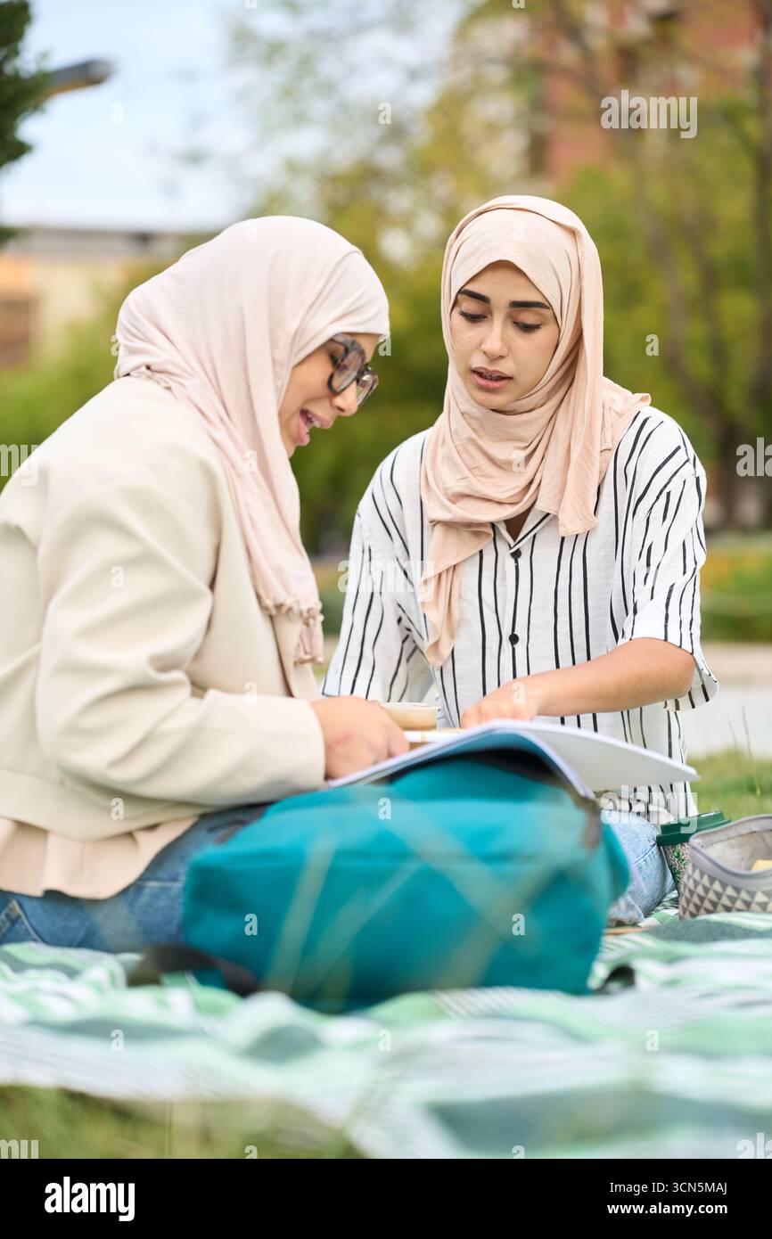 Muslim students studying together outdoors in park Stock Photo