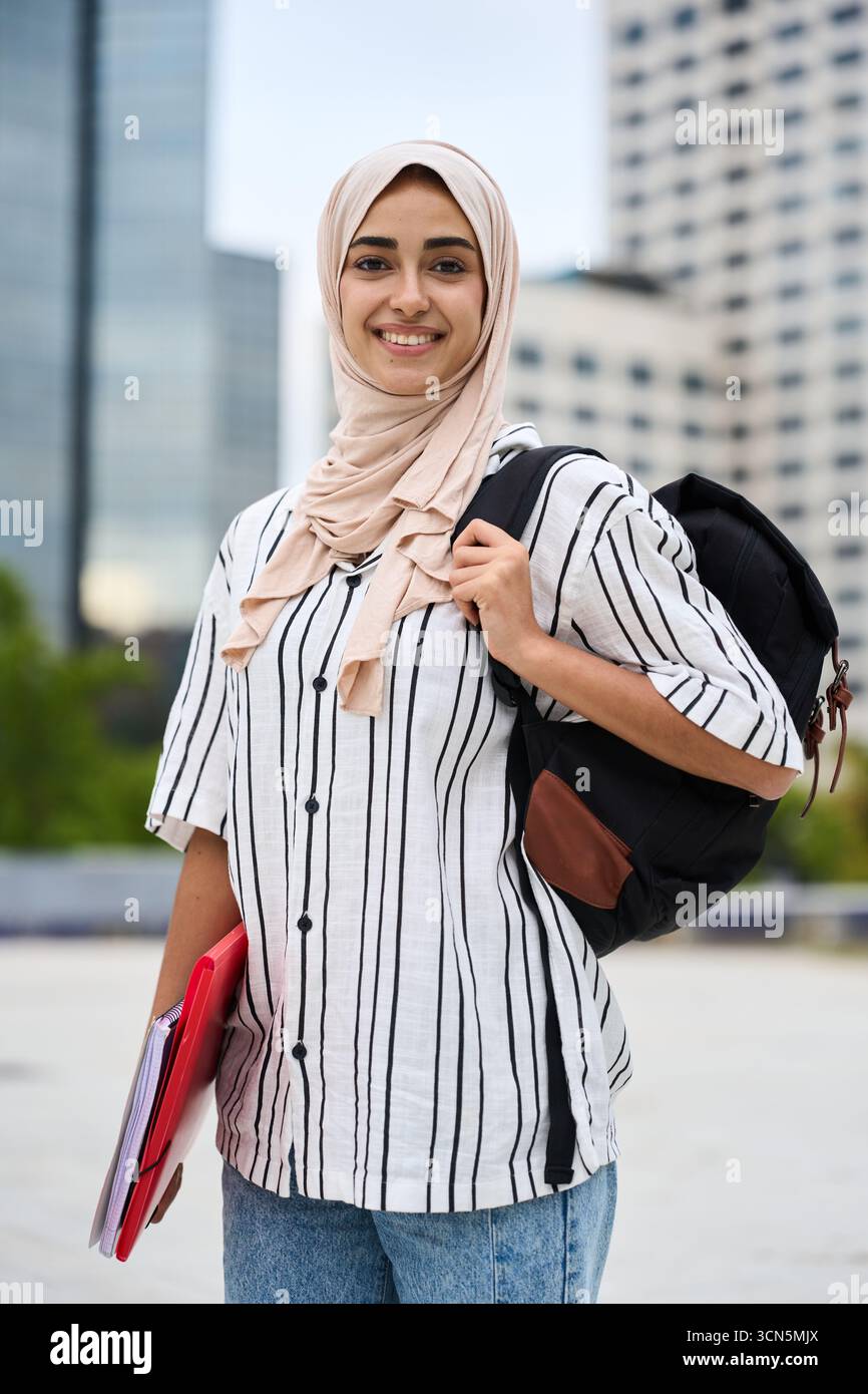 Muslim woman student smiling holding backpack and folders Stock Photo
