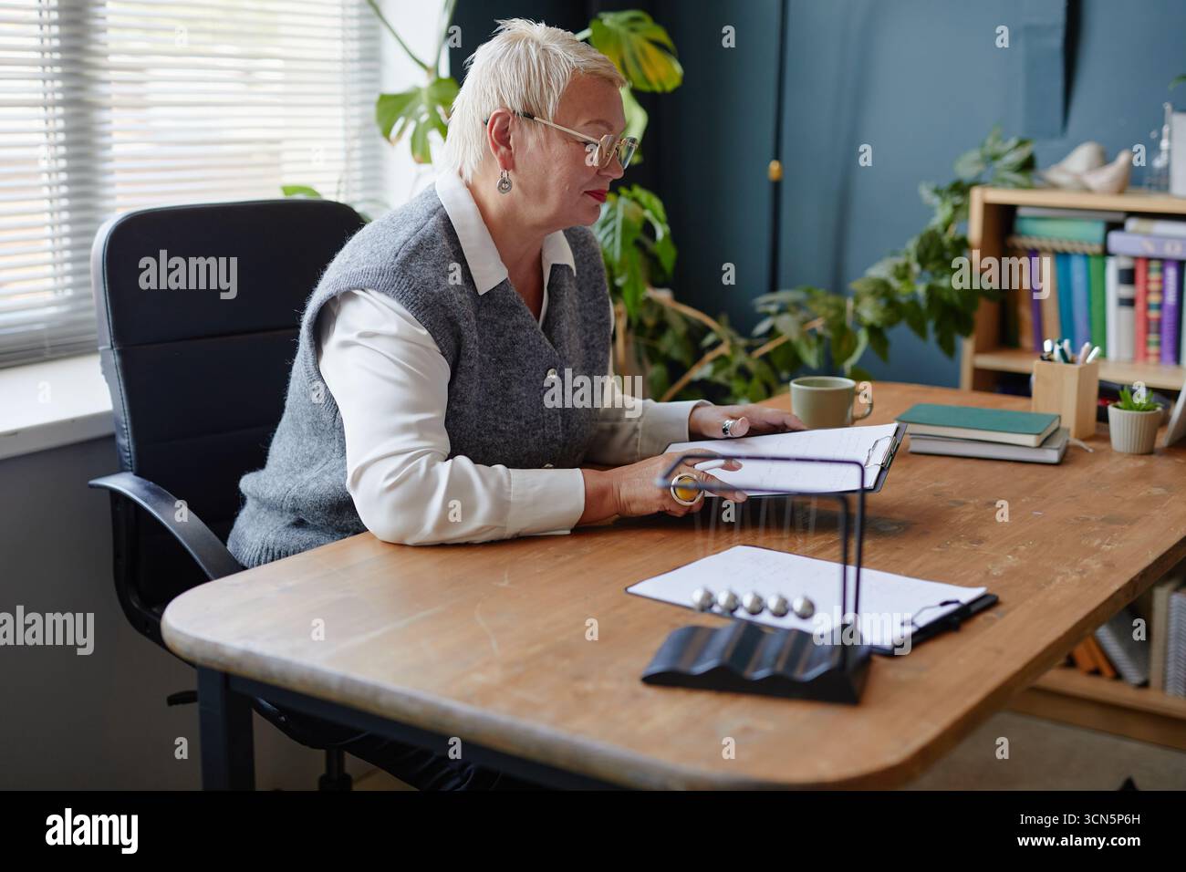 Middle Aged Caucasian Woman Reading Documents While Sitting at Office Desk Stock Photo