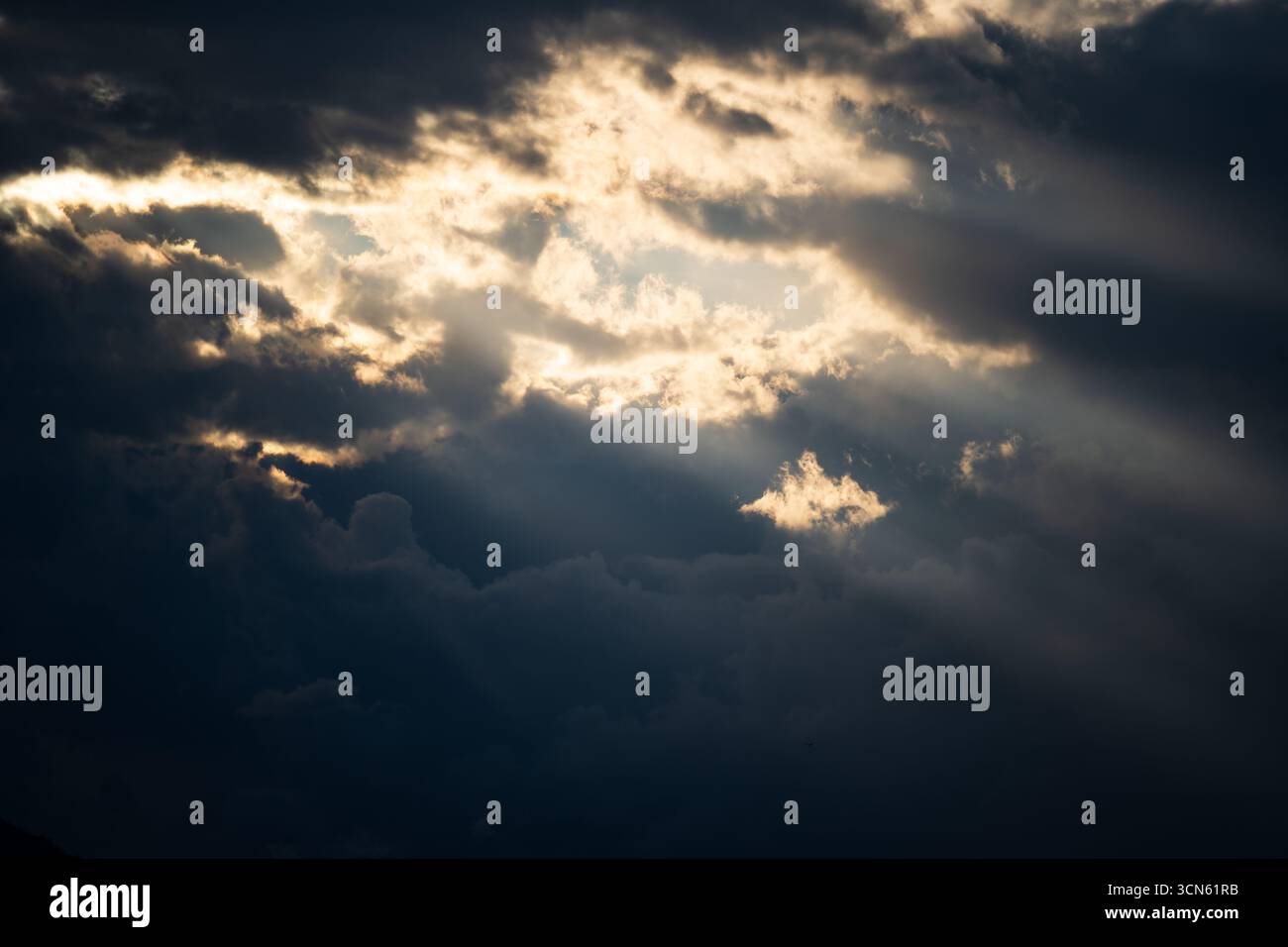 Sun light and rays breaking through thick storm clouds Stock Photo