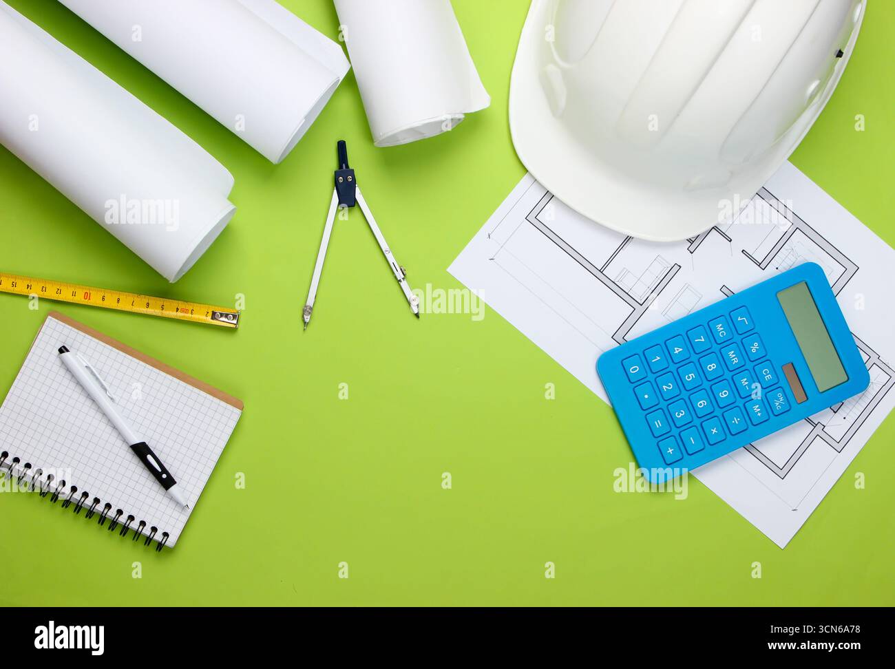 Engineering construction safety helmet, blueprint rolls, project plan and calculator on green background. Calculation of the cost building a house. To Stock Photo