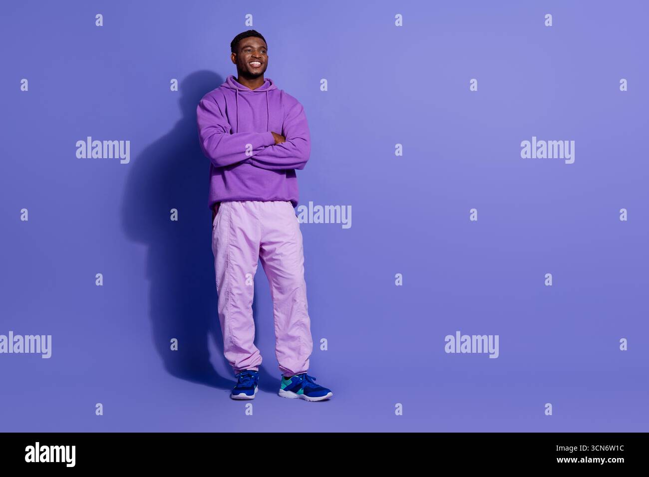 Young male model in vibrant casual purple outfit posing confidently against a violet background promoting fashionable leisure style Stock Photo