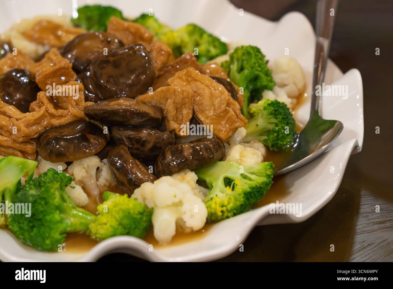 Savory vegetarian dish with tender mushrooms, steamed broccoli and cauliflower, and soybean-based ingredients served in a flavourful sauce. Stock Photo