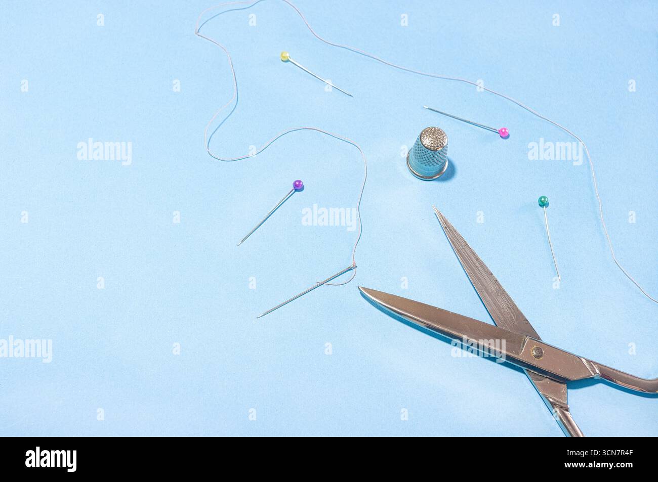 Sewing needles, thread, scissors, and thimbles. Stock Photo