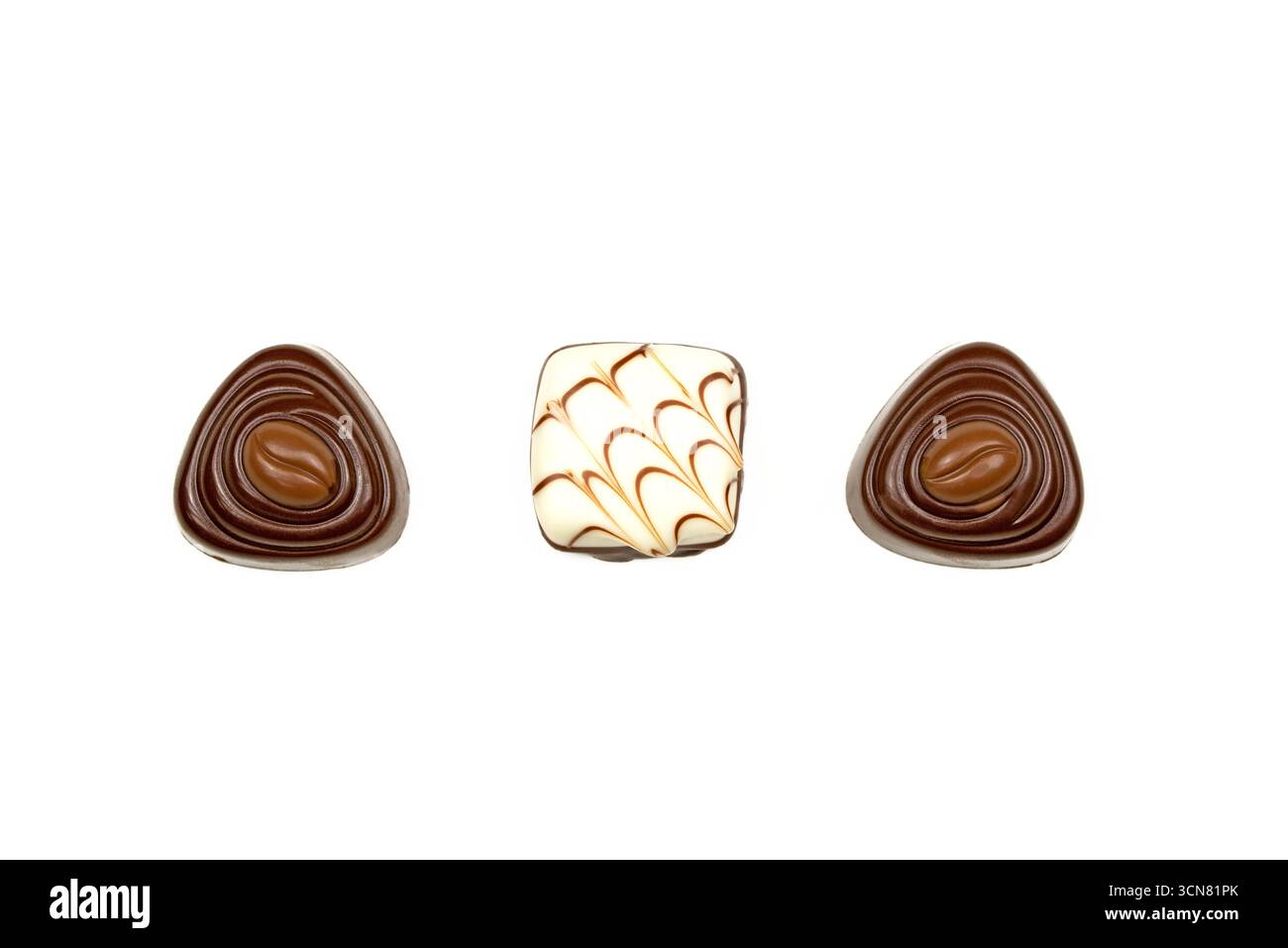 Three chocolate truffles with different shapes and designs. The ...