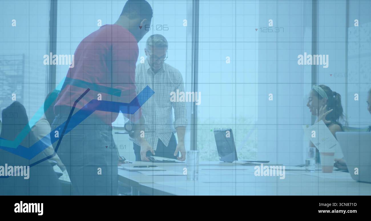 Collaborating professionals leaning over conference table in office, with laptops and documents Stock Photo