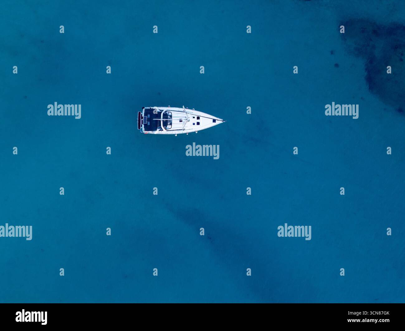 Minimalist top-down aerial view of a white yacht anchored in crystal ...