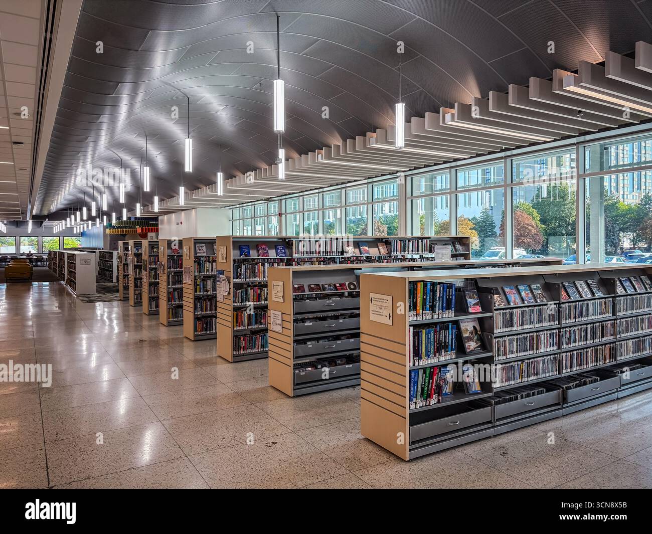 Modern library interior with rows of bookshelves, media displays, and ...