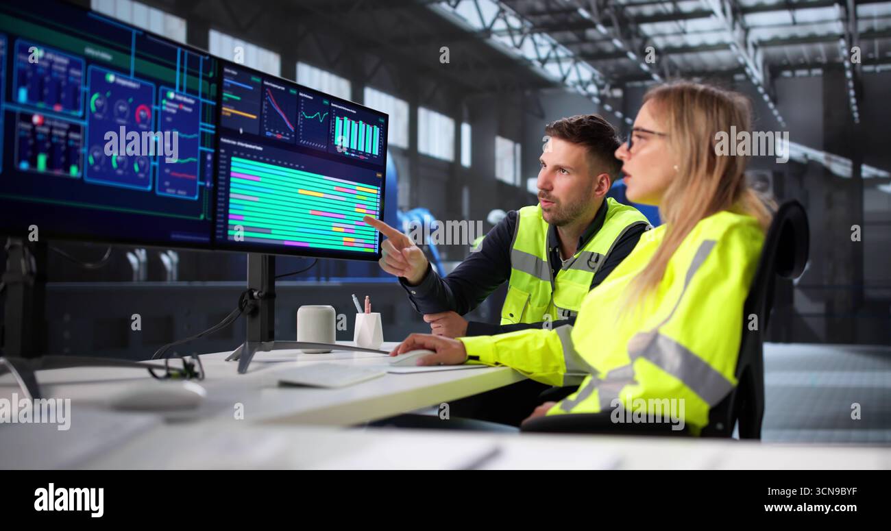Skilled Engineer Operators Using SCADA System At Industrial Plant Site. Stock Photo