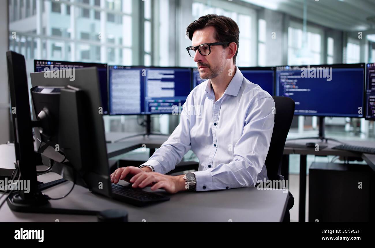 Elderly Engineer Developing Cyber Security Program On Desktop Computer Screen Stock Photo