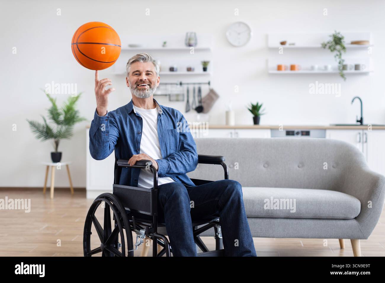 Disabled man practicing basketball skills while in wheelchair indoors Stock Photo