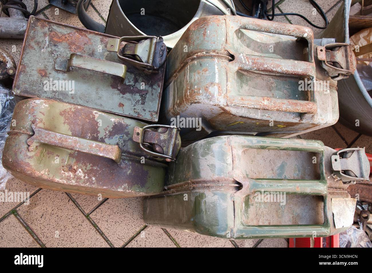 Four old metal containers with rusted handles sit on a brick floor. The ...
