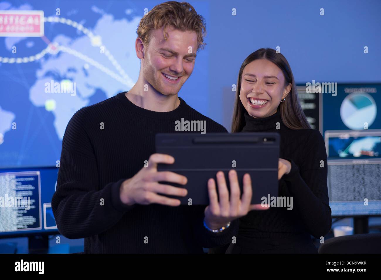 Team collaboration analyzing data on a tablet in a high-tech SOC environment Stock Photo