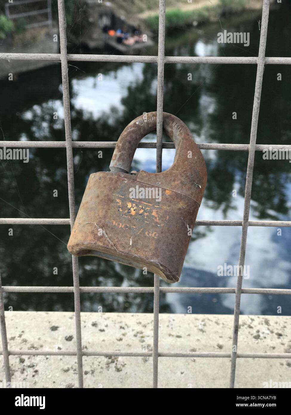 rusty old padlock on wire fence on soft focus background Stock Photo