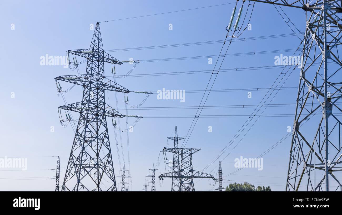 High voltage power transmission lines and steel pylons Stock Photo