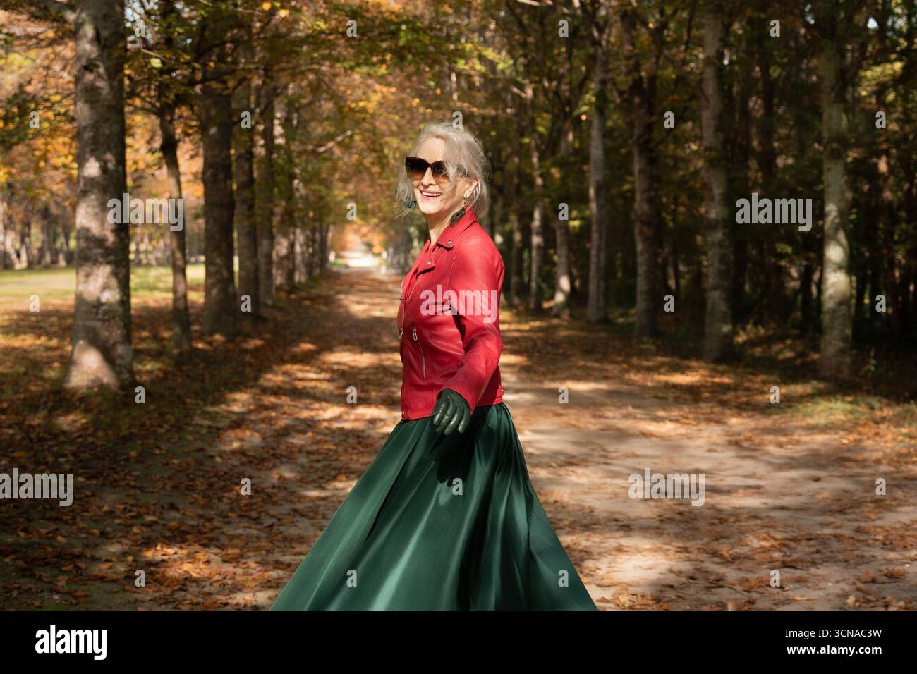 A happy sixty-year-old gray-haired woman strolls in the gardens of Versailles Stock Photo