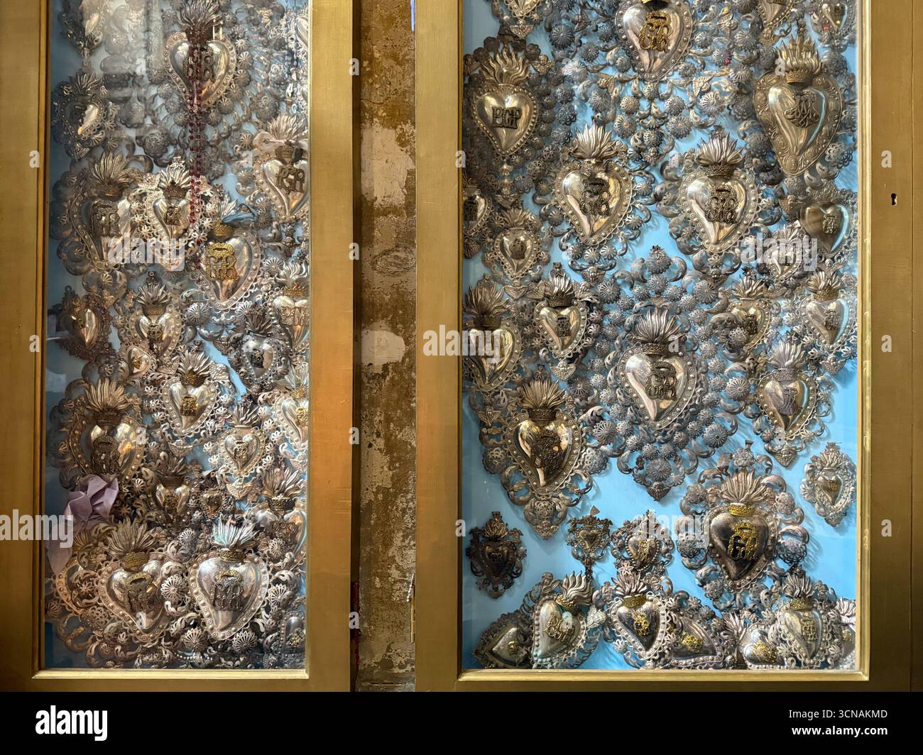 Close-up of a collection of ornate silver sacred heart ex-votos preserved in a display case inside the church of San Salvador, Venice, Veneto, Italy - Smartphone Captured Stock Image