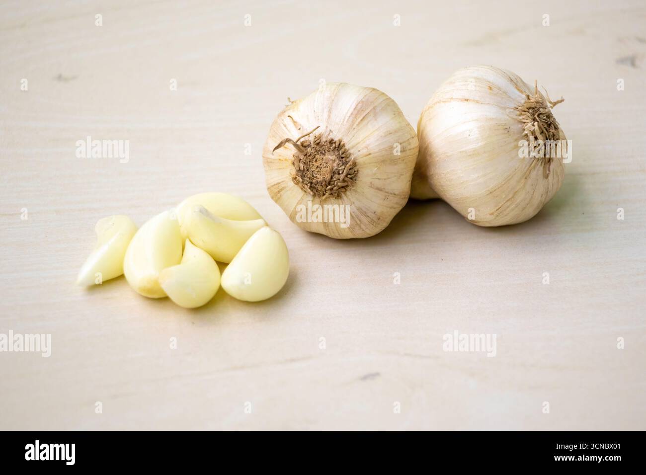 Raw garlic cloves and whole garlic on a wooden background Stock Photo ...