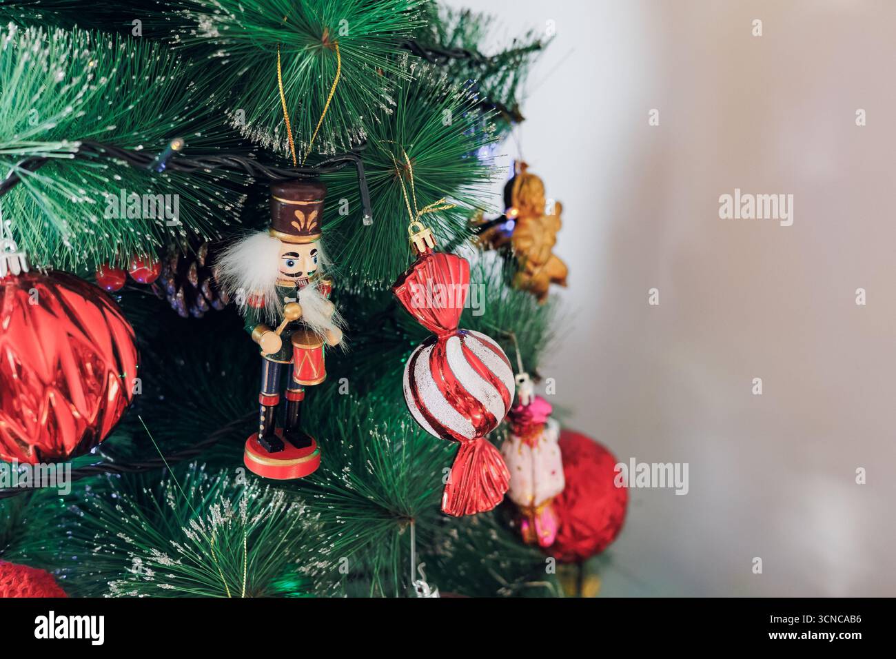 A decorated Christmas tree with a nutcracker and ornaments by a window Stock Photo