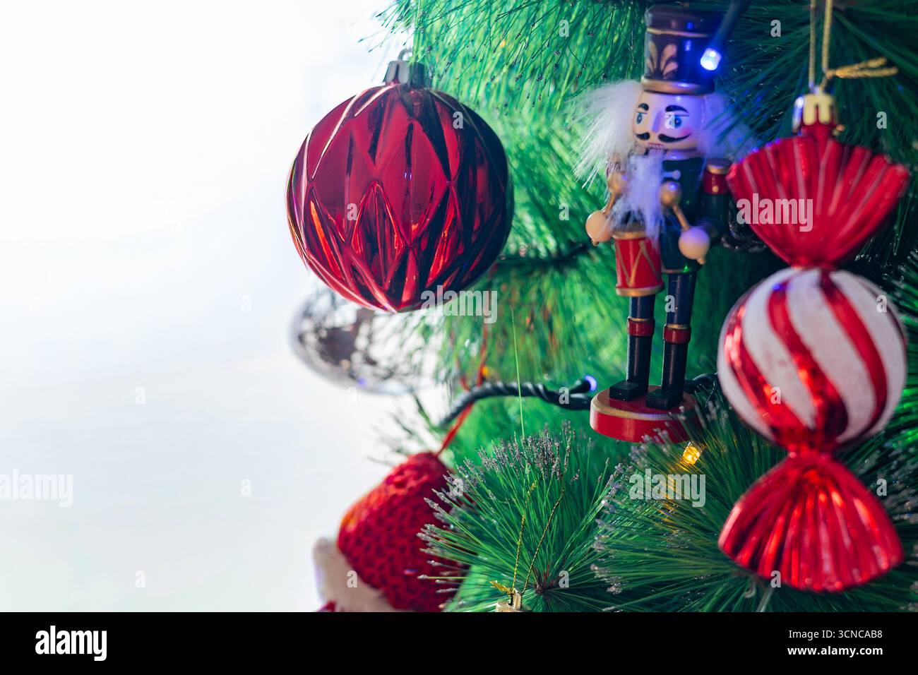A decorated Christmas tree with a nutcracker and ornaments by a window Stock Photo