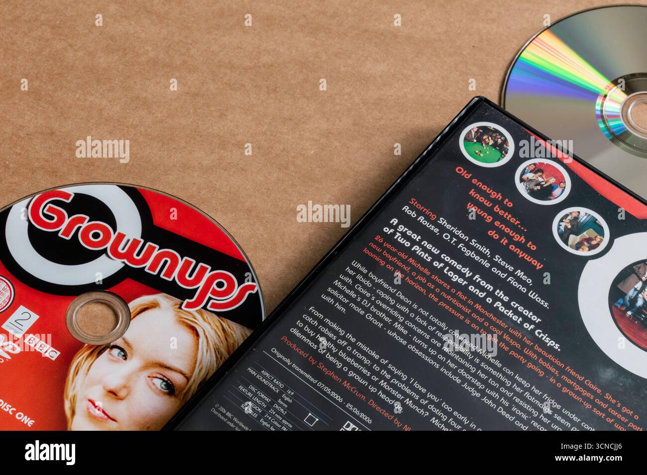 'Grownups' sitcom; DVD edition; disc with cover; description; isolated on light blank background; top angle shot. Stock Photo