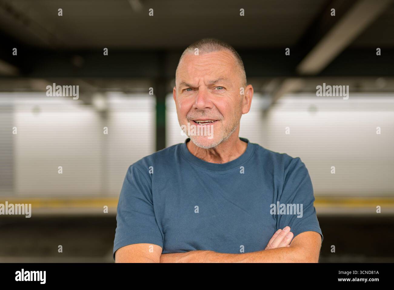 Cheerful senior man with crossed arms smiling confidently in a casual pose. Stock Photo