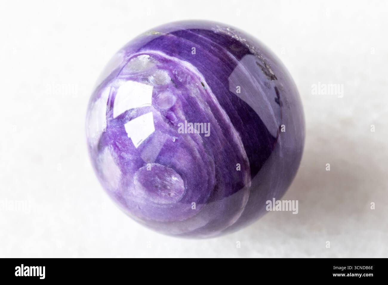 polished ball from charoite mineral on white marble background close up from Russia Stock Photo