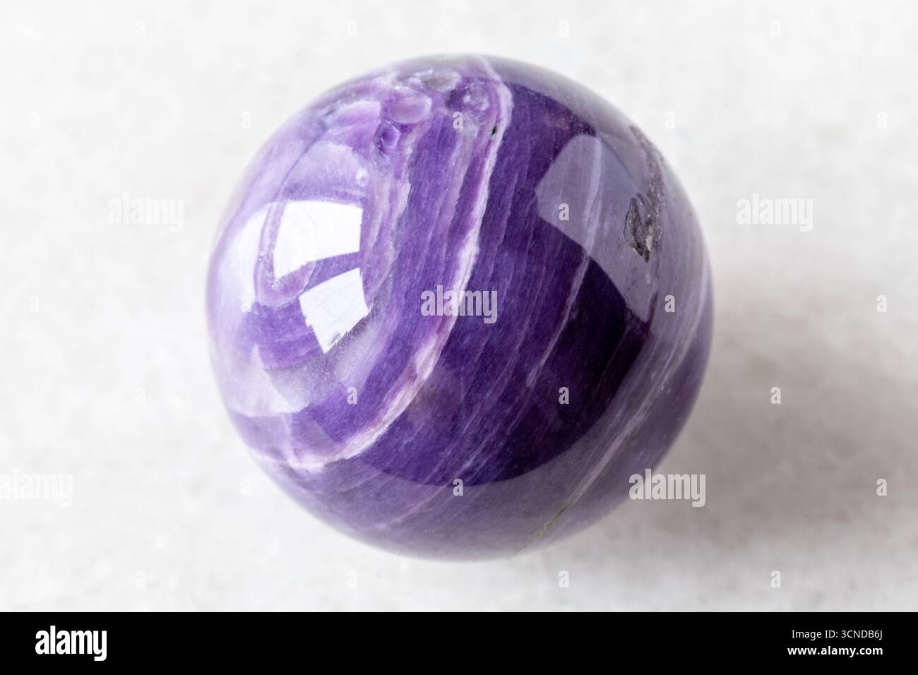 polished ball from charoite rock on white marble background close up from Russia Stock Photo