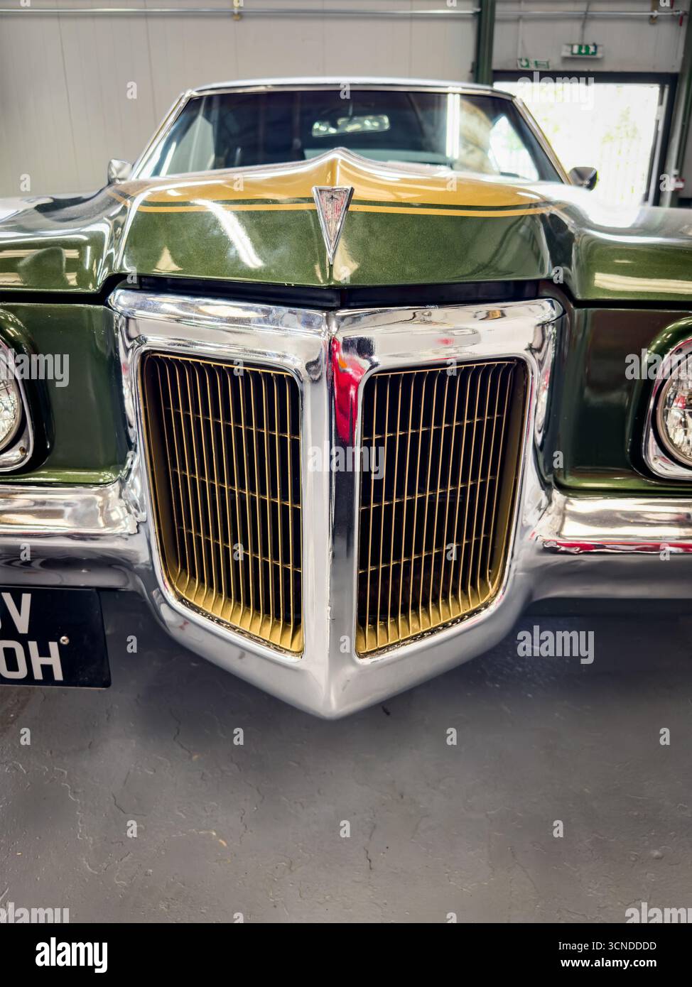 Close-up front view of a 1970 classic retro metallic green Pontiac Grand Prix vintage car with chrome details,  distinctive grille and vintage styling - Smartphone Captured Stock Image