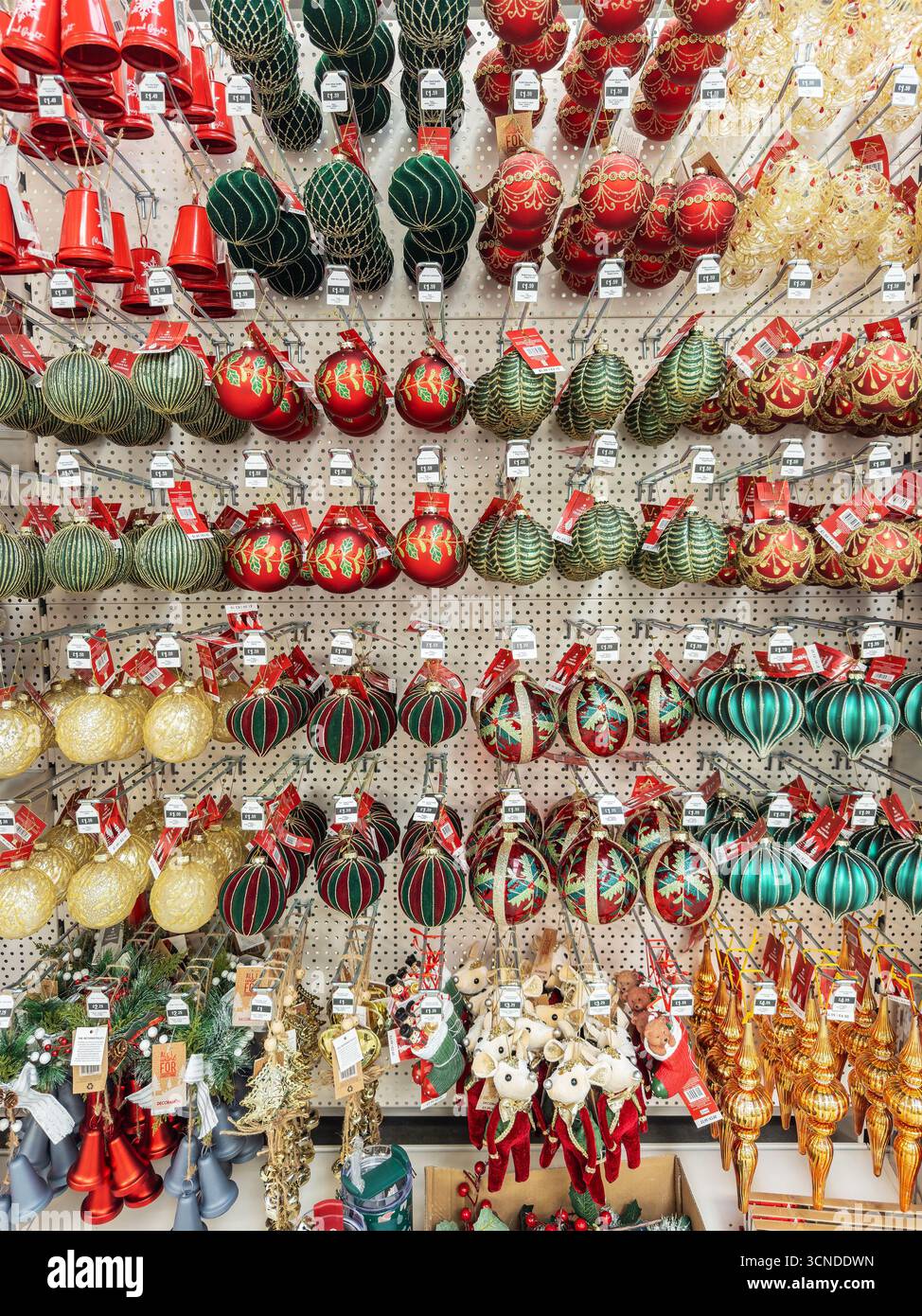 A store display with a variety of colourful hanging Christmas glass ornaments and baubles in various shapes and sizes arranged on a pegboard wall - Smartphone Captured Stock Image