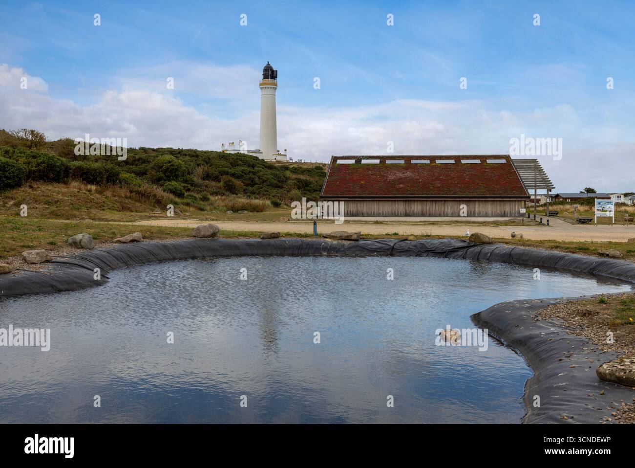 The historic Covesea Lighthouse, an iconic white tower designed by Alan Stevenson, stands on a rugged headland overlooking the Moray Firth. Stock Photo