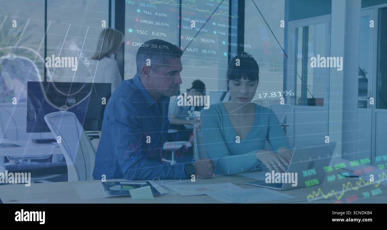 Collaborating professionals analyzing financial data overlays in open-plan office, with laptop Stock Photo
