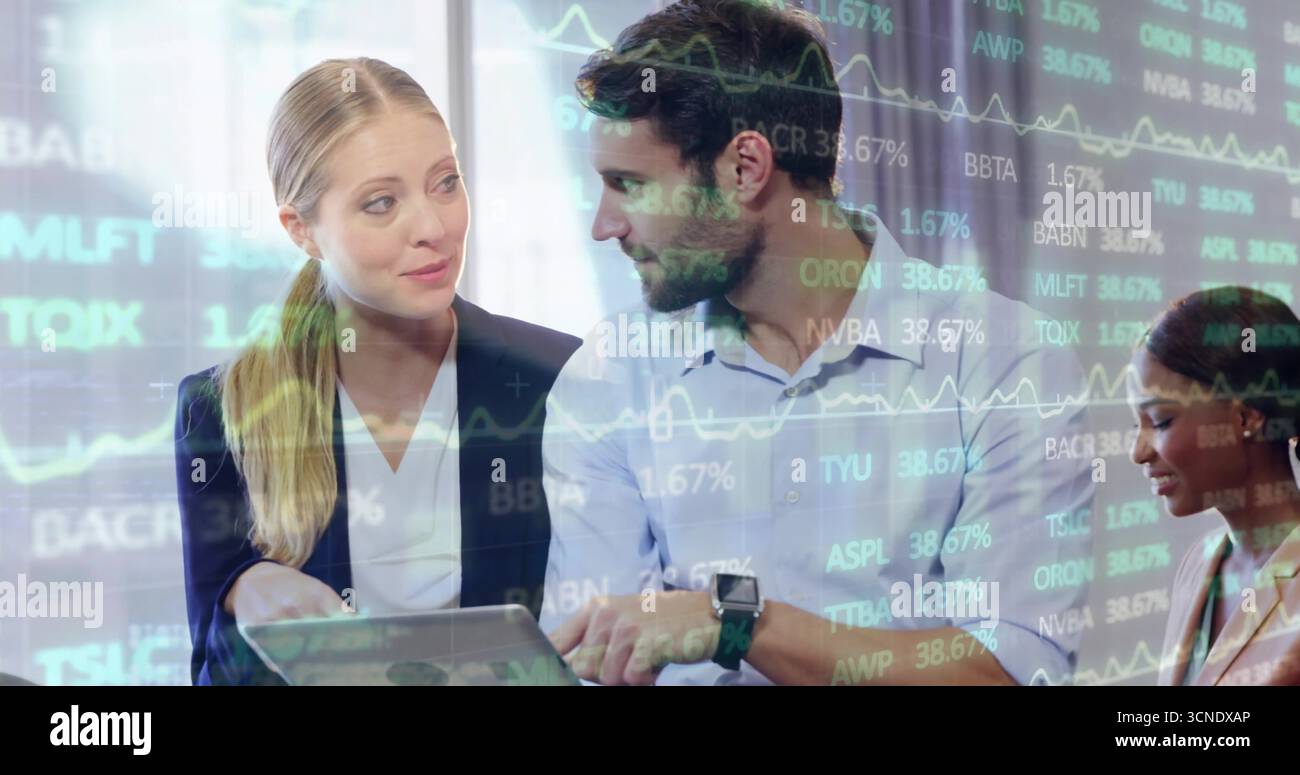 Reviewing three colleagues analyzing stock data in office boardroom, with laptop and chart overlay Stock Photo