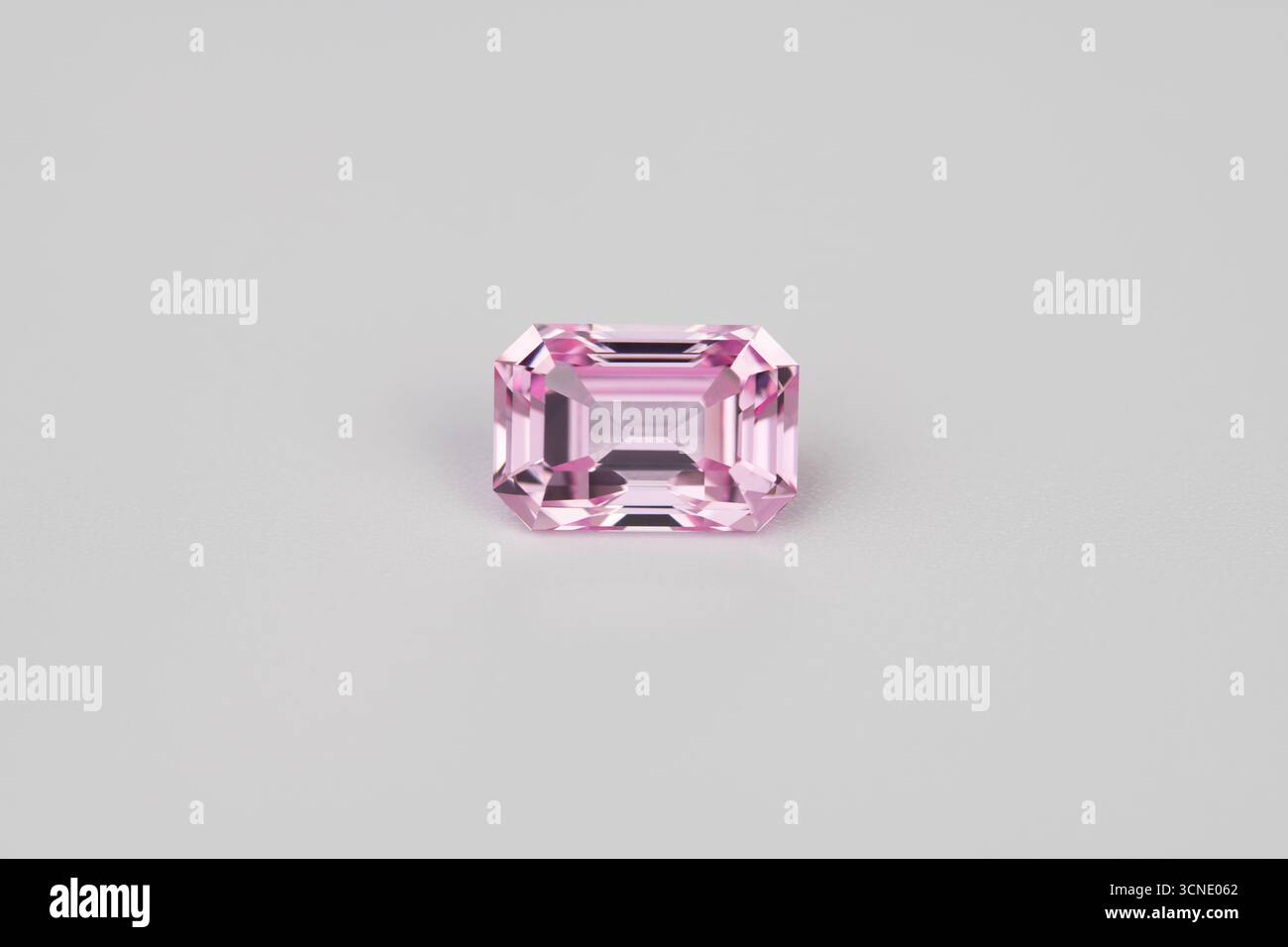 A pink gemstone sits on a white background. The stone is cut into a ...
