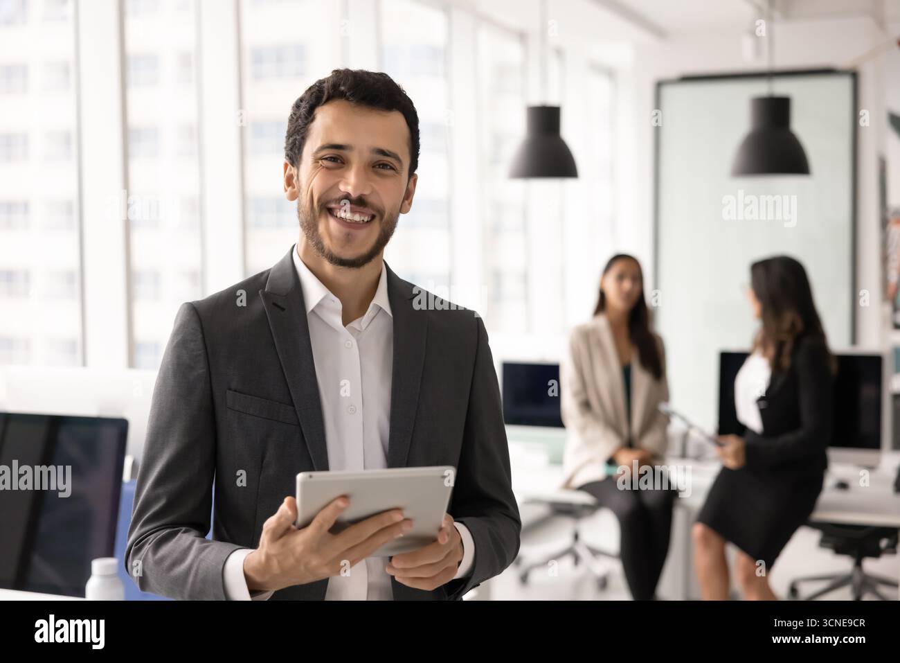 Happy young Middle Eastern project manager man holding tablet Stock Photo