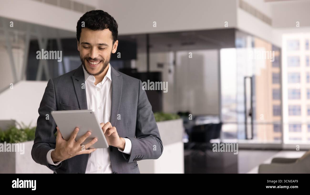 Positive young Middle Eastern male professional working with tablet Stock Photo