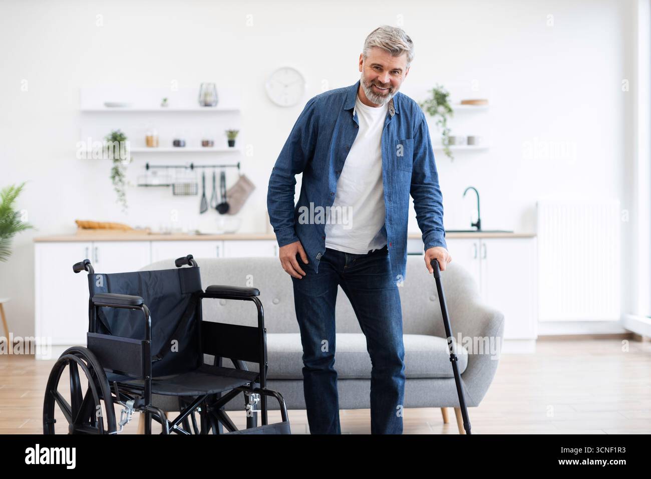 Disabled man practicing walking in modern home using cane for mobility Stock Photo