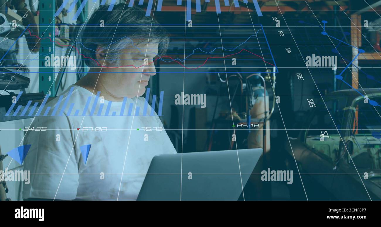 Mature technician analyzing laptop data using holographic charts in cluttered workshop Stock Photo
