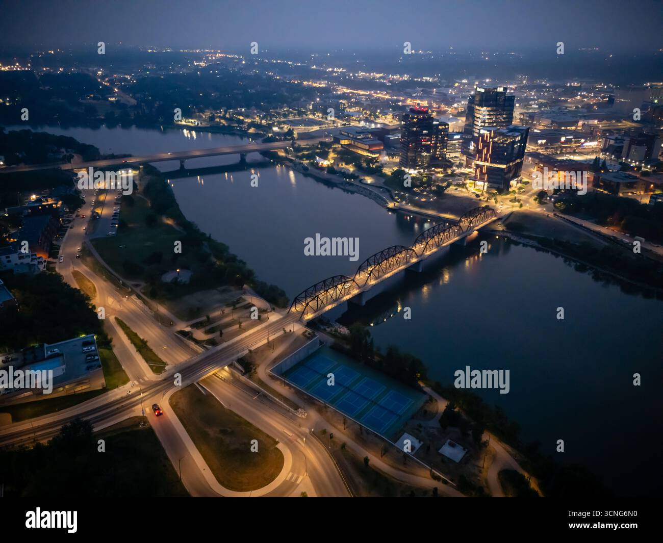 Aerial night view of downtown Saskatoon, Saskatchewan, featuring the city skyline, bridges, and illuminated streets. Stock Photo