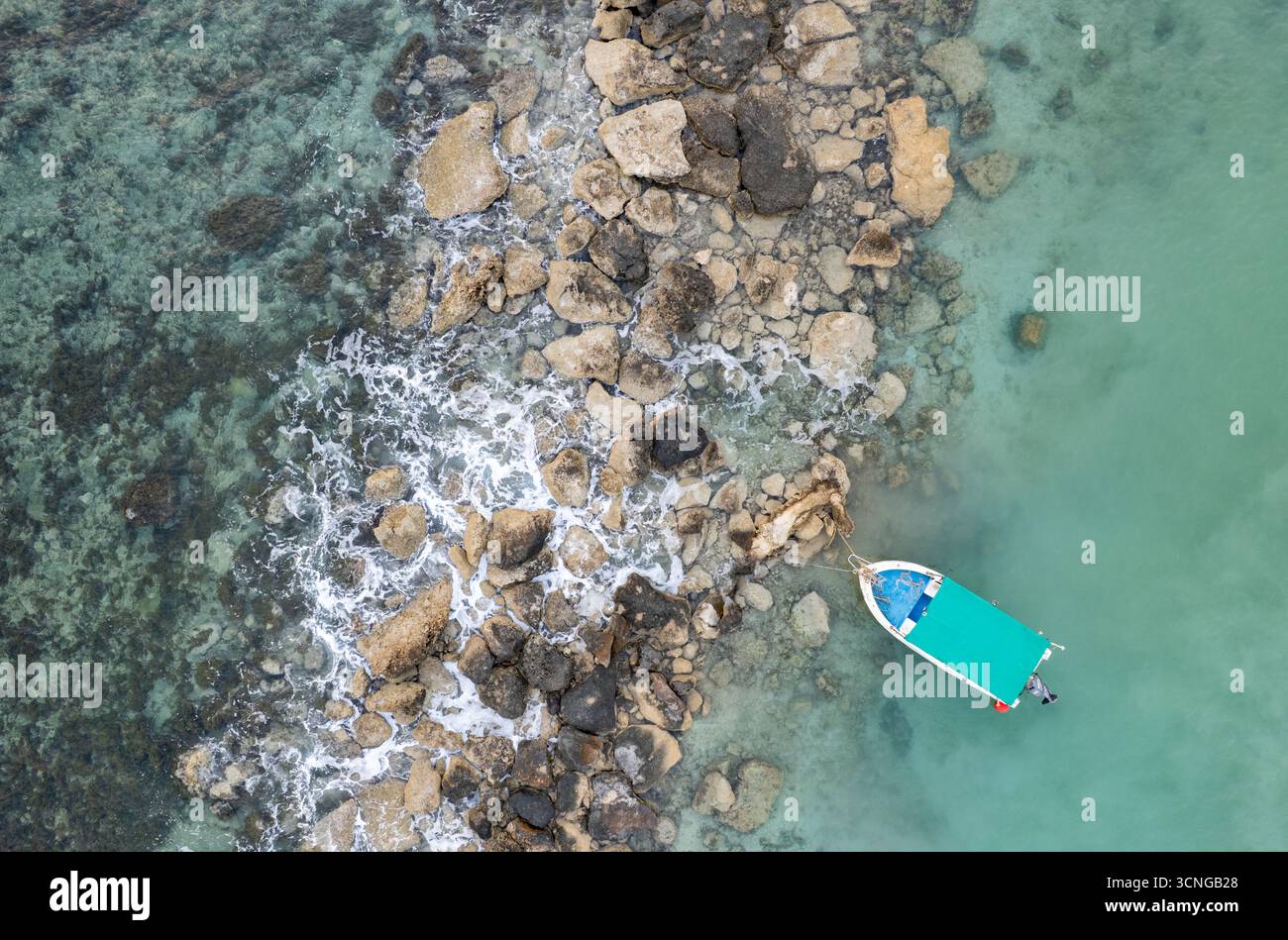Aerial view of a single fishing boat moored in calm turquoise sea ...