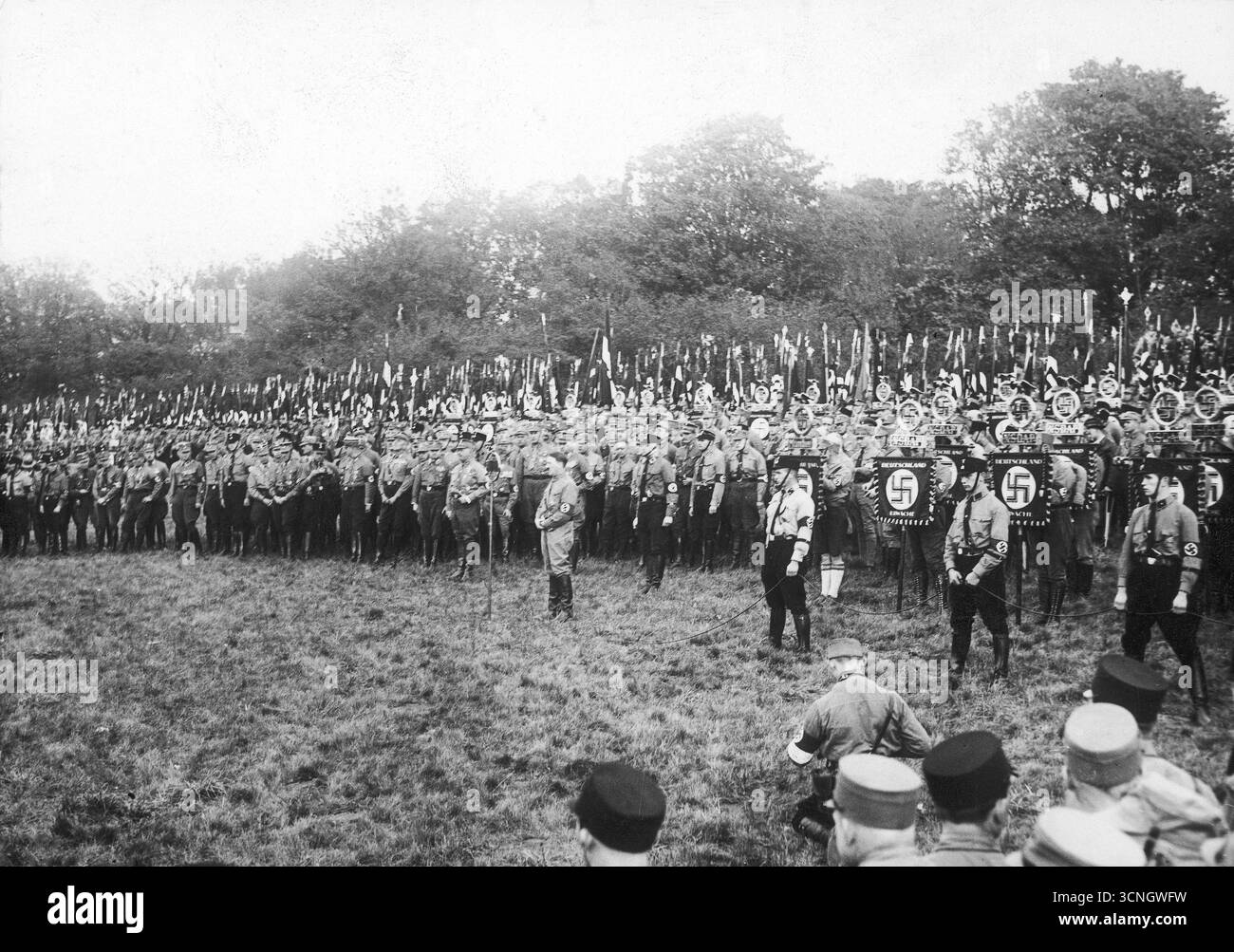 Adolf Hitler addresses SA and SS troops gathered in the square. Banners are visible. 1932 Stock Photo